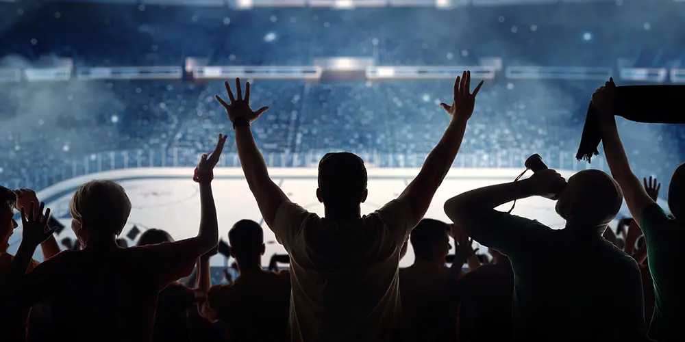Stock photo of fans in silhouette cheering at an ice hockey game